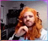 a man with red hair and a beard looks at the camera in a blurry photo