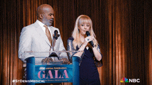 a man and woman stand behind a podium that says gala on it