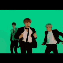 three men in suits and ties are dancing in front of a green screen .