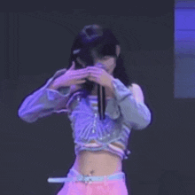 a young woman is covering her face with her hands while dancing on a stage .