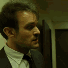 a man wearing a suit and tie has blood on his face
