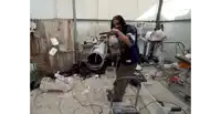 a man with dreadlocks is working on a large pipe in a messy room