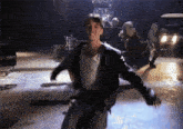 a man in a leather jacket and white tank top is dancing on a stage