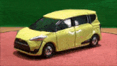 a yellow toy car is sitting on a red surface with a green background