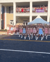 a group of women are dancing in front of a building that has a sign that says lulugang