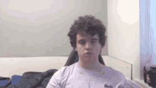 a young man with curly hair is sitting in a chair in a room .
