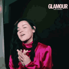 a woman in a pink dress is clapping in front of a glamour advertisement