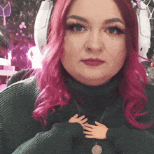 a woman with pink hair is wearing a green turtleneck sweater