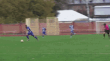 a group of people are playing soccer on a field with buildings in the background .