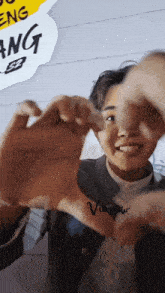 a person making a heart shape with their hands with the name visnew written on their wrist
