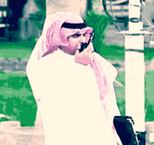 a man talking on a cell phone while wearing a head scarf
