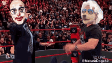 a man in a suit and tie is standing next to a man in sunglasses in a wrestling ring .