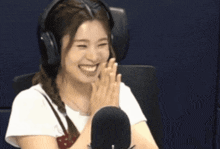 a woman wearing headphones is smiling and clapping her hands