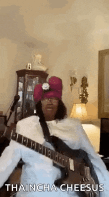 a man is playing a guitar and wearing a red hat .
