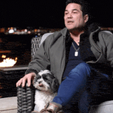 a man is sitting in a chair with a small dog on his lap