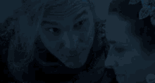 a man and a woman are looking at each other in a dark room .