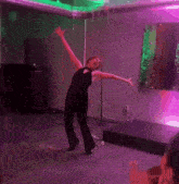 a woman in a black jumpsuit is dancing in a room with green and purple lights