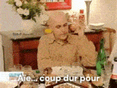 a man is sitting at a table with a bottle of water and a plate of food and the words coup dur pour on the bottom