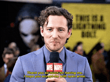 a man in a suit is holding a marvel microphone and says thank you so much for having me