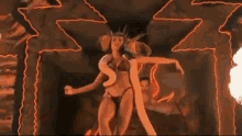 a woman in a bikini is dancing in a dark room with a snake in her mouth .