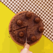 a person is cutting a slice of chocolate cake with a knife