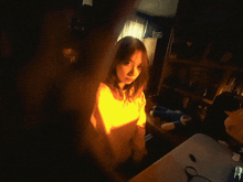 a woman is standing in a dark room with a stuffed animal on the desk
