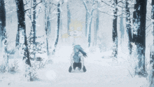 a man is kneeling in the snow in a forest with a cartoon character behind him