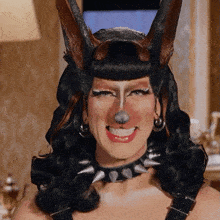 a woman wearing a dog costume and a spiked collar smiles for the camera