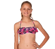 a young girl in a bikini top is standing with her hands on her hips and smiling .