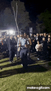 a man in a cowboy hat holds a stick in front of a crowd
