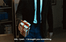 a man in a suit and tie is holding a gift and says um i just brought you something