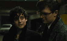two men are standing next to each other and one of them has glasses on