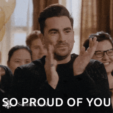 a man applauds in front of a sign that says 