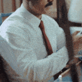 a man in a white shirt and red tie is using a cell phone