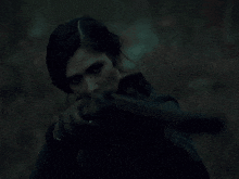 a woman holding a gun in her hand in the dark