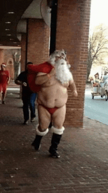 a man in a santa costume is walking down a sidewalk