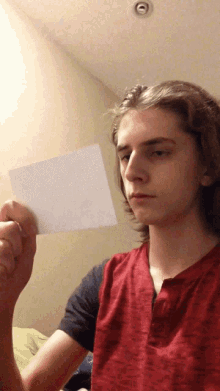 a man in a red shirt is holding a piece of paper