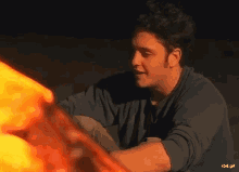 a man is sitting in front of a fire .