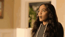 a girl with a surprised look on her face is wearing a grey hoodie