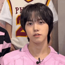 a young man wearing a pink sweater has a microphone on his neck