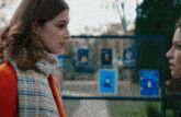 two women are standing next to each other in front of a fence