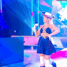 a woman in a blue dress and cowboy hat is standing on a stage