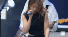 a woman is singing into a magenta music 360 sign