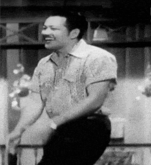 a black and white photo of a man in a plaid shirt dancing .