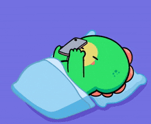a green cartoon character is sleeping with a phone in its mouth