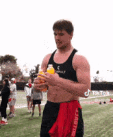 a shirtless man is holding a bottle of orange juice on a football field .