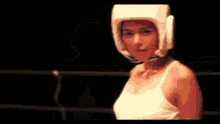 a woman wearing a boxing helmet is standing in a ring .