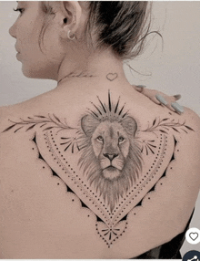 a woman has a tattoo of a lion 's head on her back