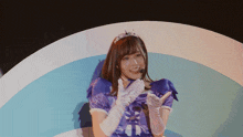 a woman in a purple dress and white gloves wears a tiara