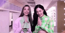 two girls are standing next to each other in a hallway .